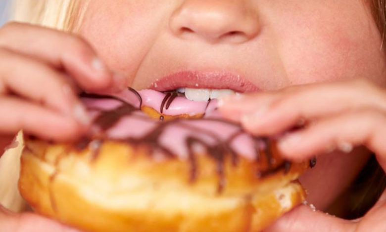 Girl eating a Doughnut - Baby Root Canal Treatment Aurora & Denver