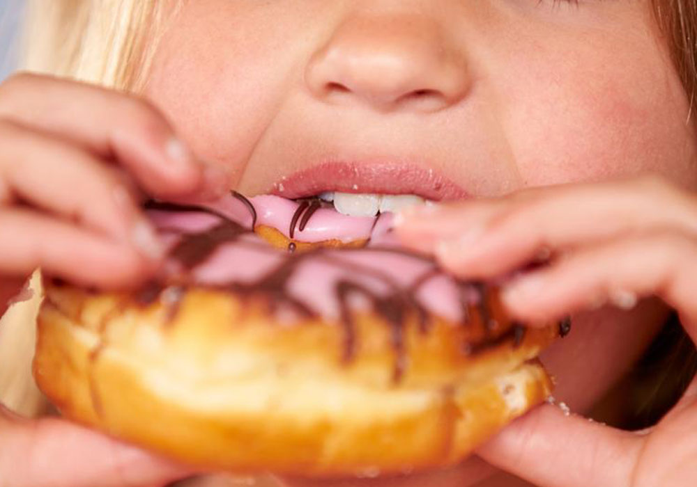 Girl eating a Doughnut - Baby Root Canal Treatment Aurora & Denver